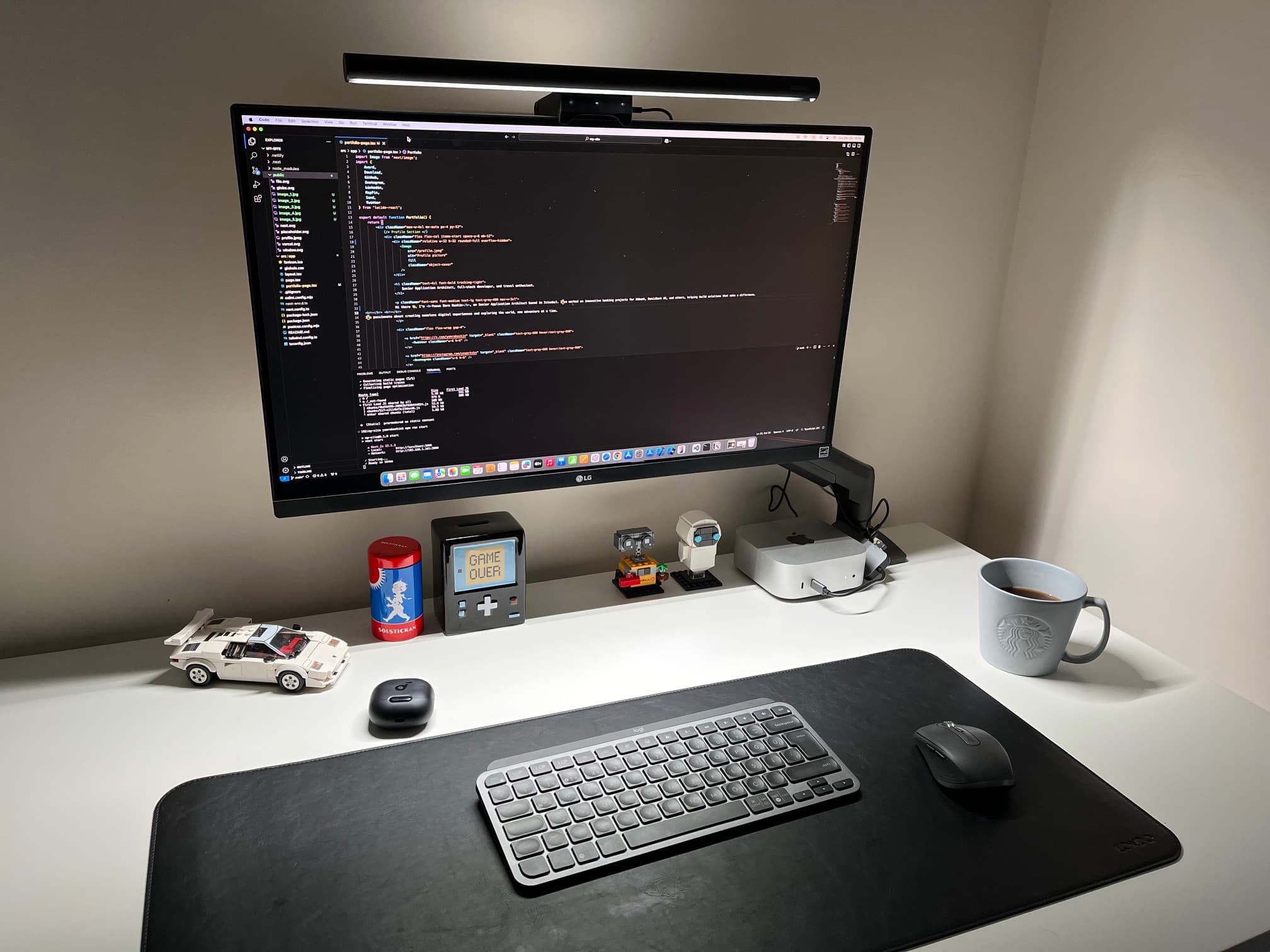 Kod gösteren büyük monitör, klavye ve mouse ile sade bir ev ofisi masası